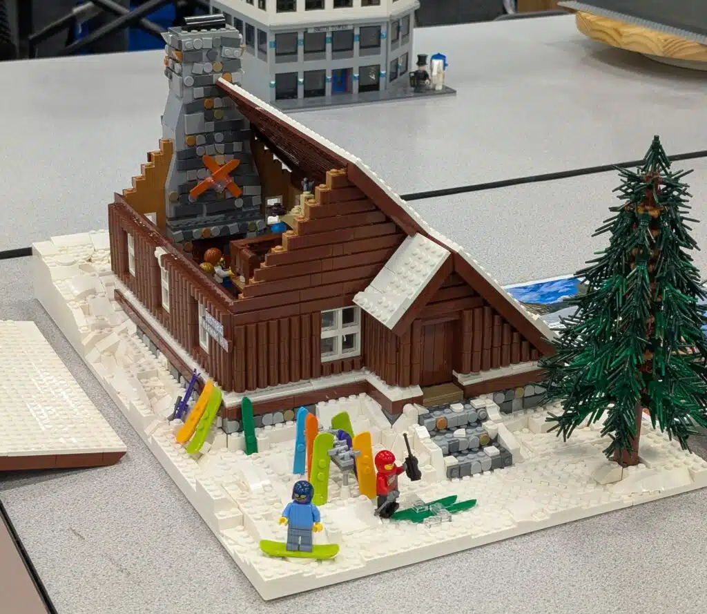 LEGO creation titled "Historic Warming Hut at Mount Hood Ski Bowl" depicts a log cabin in the snow with a section of roof removed to show a cozy interior.